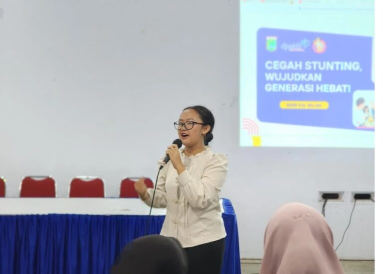 Woman in a white blazer speaks into a microphone at a conference, with a projection slide about preventing stunting in the background.